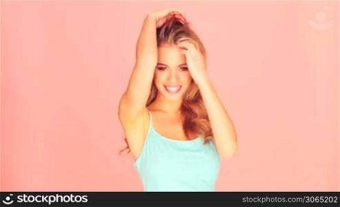 Beautiful serene blonde woman in casual blue dress isolated on pink.