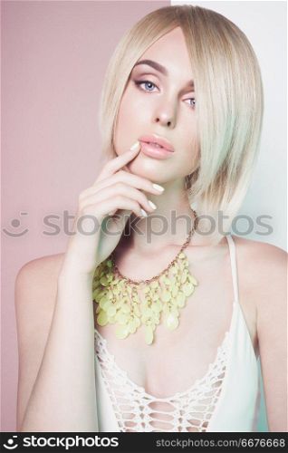 Beautiful sexy blonde with professional classic make-up pose in photography studio. Sensual stylish woman in erotic white dress. Blue-eyed lady with perfect lips in modern colour jewelry