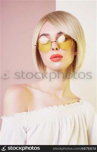                                Beautiful sexy blonde with professional classic make-up pose in photography studio. Sensual stylish woman in erotic white dress. Blue-eyed lady with perfect lips in modern colour sunglasses