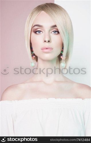 Beautiful sexy blonde with professional classic make-up pose in photography studio. Sensual stylish woman in erotic white dress. Blue-eyed lady with perfect lips and pink lipstick.