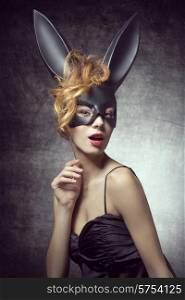 Beautiful, sexy, charming woman in carnival, black costume of bunny, with wild hairstyle and red lips.