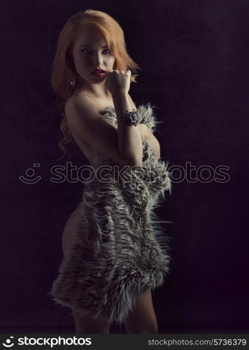 Beautiful, sexy, ginger girl cover her nude body with fluffy fur. she is looking in camera with a very sensual look