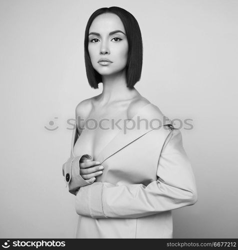 Beautiful sexy woman in white autumn coat. Young pretty brunette pose in studio in vintage clothes. Fashionable lady with professional classic hairstyle. Fashion art portrait.