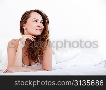 Beautiful sexy woman lying on her stomach on her bed over white