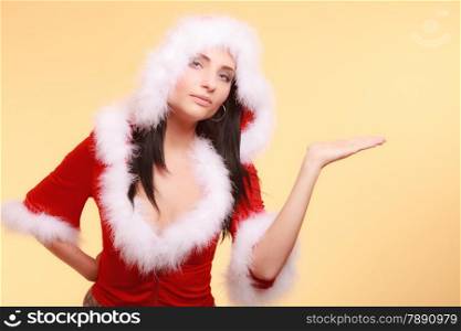 Beautiful sexy woman wearing santa claus costume clothes showing empty copy space for product presenting with open hand palm on yellow background