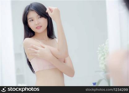 Beautiful sexy young asian woman looking mirror applying cream on arms and message, beauty girl applying body lotion skin care for health and soft hydration, treatment and cosmetic with moisturizer.