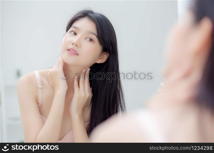 Beautiful sexy young asian woman looking mirror applying cream on neck and message, beauty girl applying body lotion skin care for health and soft hydration, treatment and cosmetic with moisturizer.