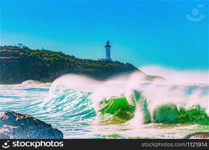 Beautiful shot ocean waves splashing to the shore with a rock formation under the clear sky