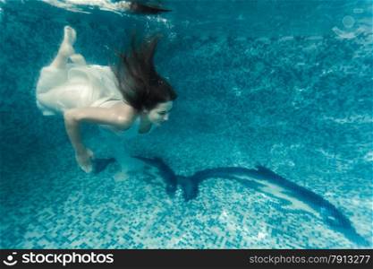 Beautiful shot of sexy woman in white cloth diving underwater at pool