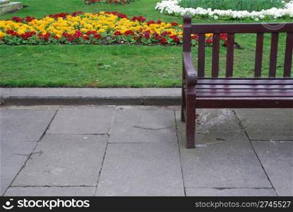 beautiful sidewalk scene with a wooden bench and gorgeous flowers at the background