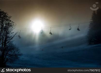 Beautiful silhouette photo of ski lifts shot against bright sun in mountains