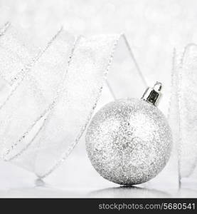 Beautiful silver christmas ball on abstract glitter background close-up