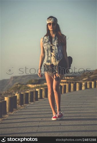 Beautiful skate girl walking while holding a skateboard