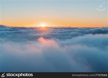 Beautiful Sky Backgound. Orange Sun Sets Behind Fluffy White Clouds. Amazing Sunset View Among Heaven. Beauty of Nature.. Above Clouds Background
