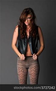 Beautiful slender brunette in a black leather vest and knit tights