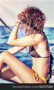 Beautiful slim woman sitting on sailboat in bright sun light, enjoying summer vacation in sea cruise, freedom and active lifestyle concept