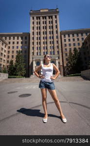 Beautiful slim woman standing on street against high building