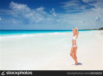 Beautiful slim woman tanning on the beach, standing on clean white sand, taking sunbath, enjoying dayspa, summer holiday and vacation concept