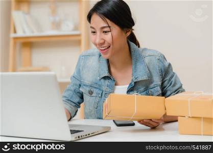 Beautiful smart Asian young entrepreneur business woman owner of SME online checking product on stock and save to computer working at home. Small business owner at home office concept.
