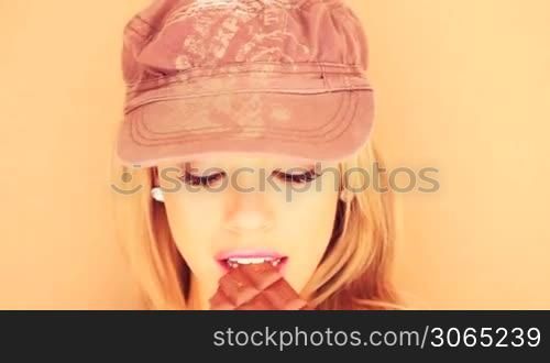 Beautiful smiling blond woman eating a large bar of chocolate