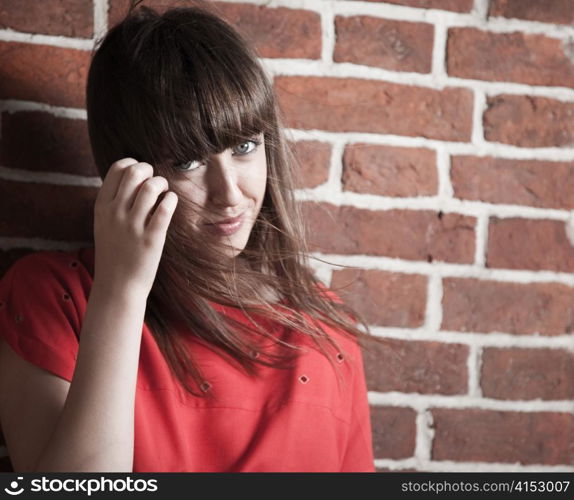 Beautiful smiling brunette woman in front of a brick wall