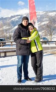 Beautiful smiling couple hugging on winter resort at Austrian Alps