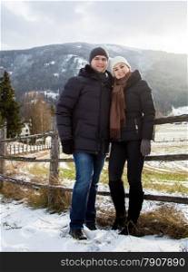 Beautiful smiling couple in love posing against Austrian Alps covered in snow