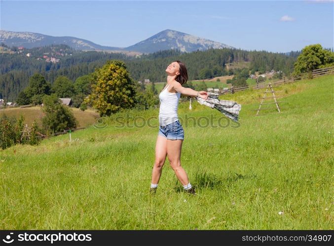 Beautiful smiling girl in country style dress posing at grass meadow