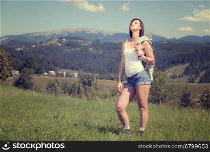 Beautiful smiling girl in country style dress standing at grass meadow