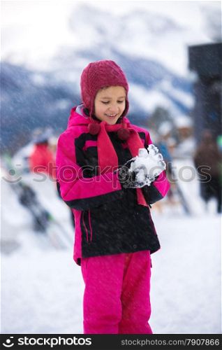 Beautiful smiling girl posing against high mountains with snowball