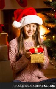 Beautiful smiling girl posing with golden Christmas gift box