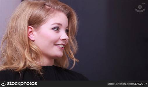 Beautiful smiling girl with blond wavy hair by hairdresser. Young woman in hairdressing beauty salon. Hairstyle.