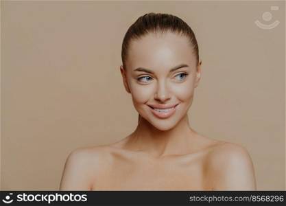 Beautiful smiling girl with clean skin, natural make-up, and white teeth on beige background. Fashion, beauty, make-up, cosmetics.