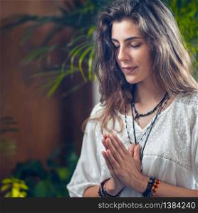 Beautiful smiling mindfulness young girl standing with her eyes close and hands in a prayer position or Namaste gesture.