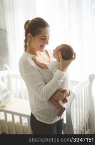 Beautiful smiling mother holding on hands and looking at her baby