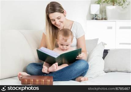 Beautiful smiling mother reading story to her 9 months old baby boy