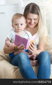 Beautiful smiling mother reading story to her 9 months old baby boy