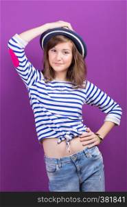 beautiful smiling teen girl in a hat posing on a purple background