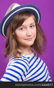 beautiful smiling teen girl in a hat posing on a purple background