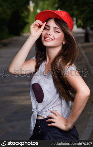 beautiful smiling teen model on street. red cap, grey t-shirt, dark blue shorts