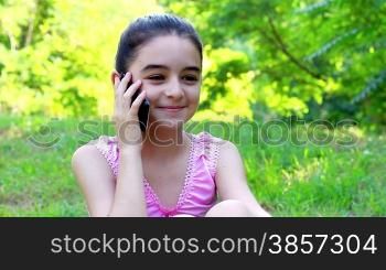 Beautiful smiling teenage girl talking on mobile phone, in summer green park.