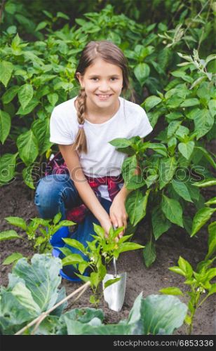 Beautiful smiling teenage girl working at garden with hand shovel