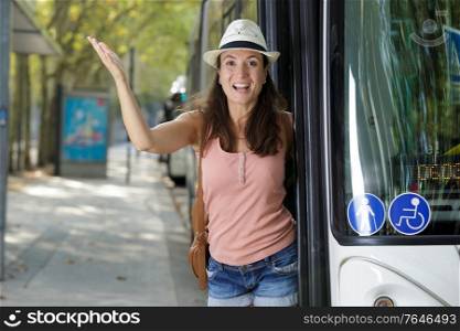 beautiful smiling waving young woman entering bus