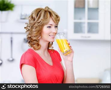 Beautiful smiling woman drinking fresh orange juice - indoors