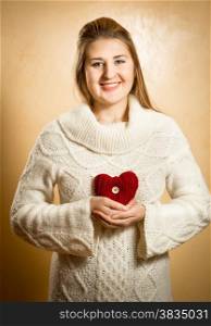 Beautiful smiling woman holding big red knitted heart