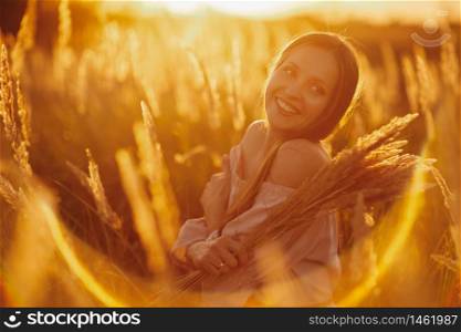 Beautiful smiling woman in a field at sunset. Young woman Girl in field in Sunset in spring, summer landscape background Springtime Summertime. selective focus. Young woman Girl in field in Sunset in spring, summer landscape background Springtime Summertime. Beautiful smiling woman in a field at sunset. selective focus