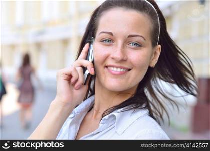 beautiful smiling woman is talking phone at sunny street