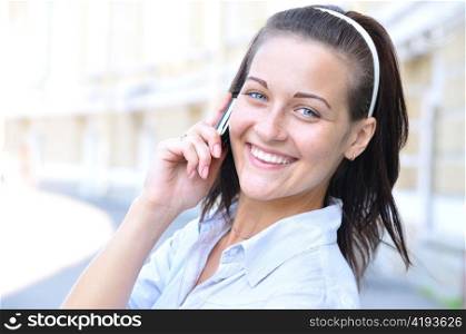 beautiful smiling woman is talking phone at sunny street