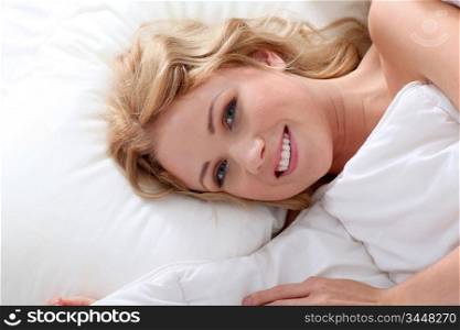 Beautiful smiling woman laying in bed
