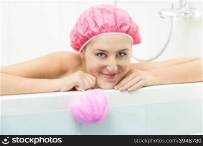Beautiful smiling woman lying in bath and looking at camera